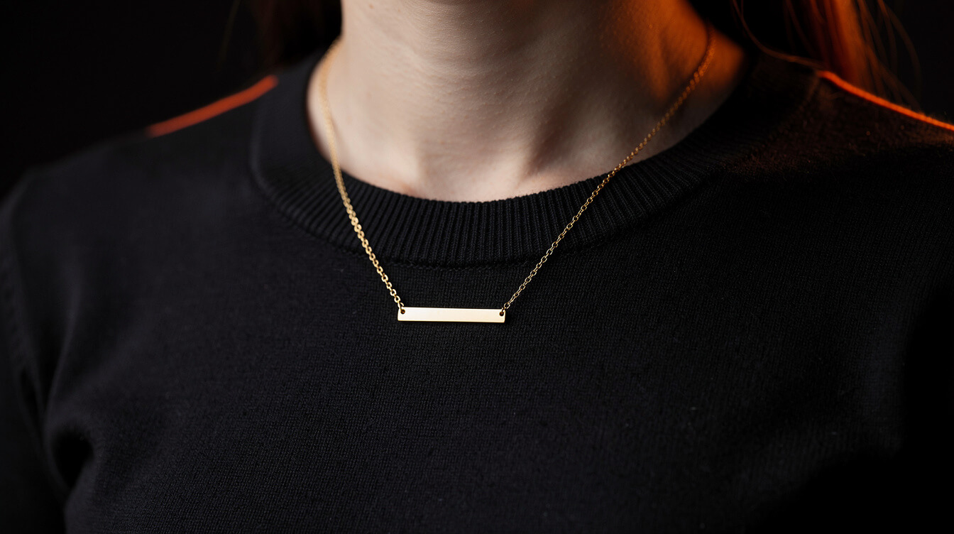 Blank gold-tone bar necklace worn at the collarbone